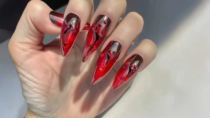 Custom red stiletto nails with bold black and metallic details